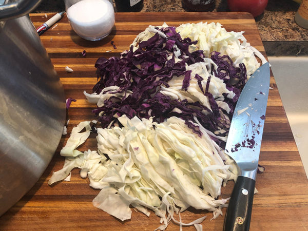 sliced cabbage on a cutting board next to a knife