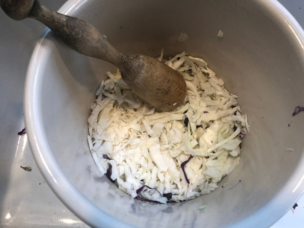 cabbage in a crock with a wooden tamper