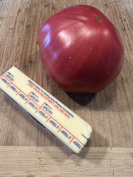 Large tomato next to a stick of butter