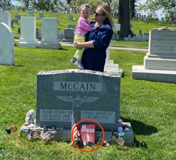 Meghan McCain with her book propped up against her dad's tombstone