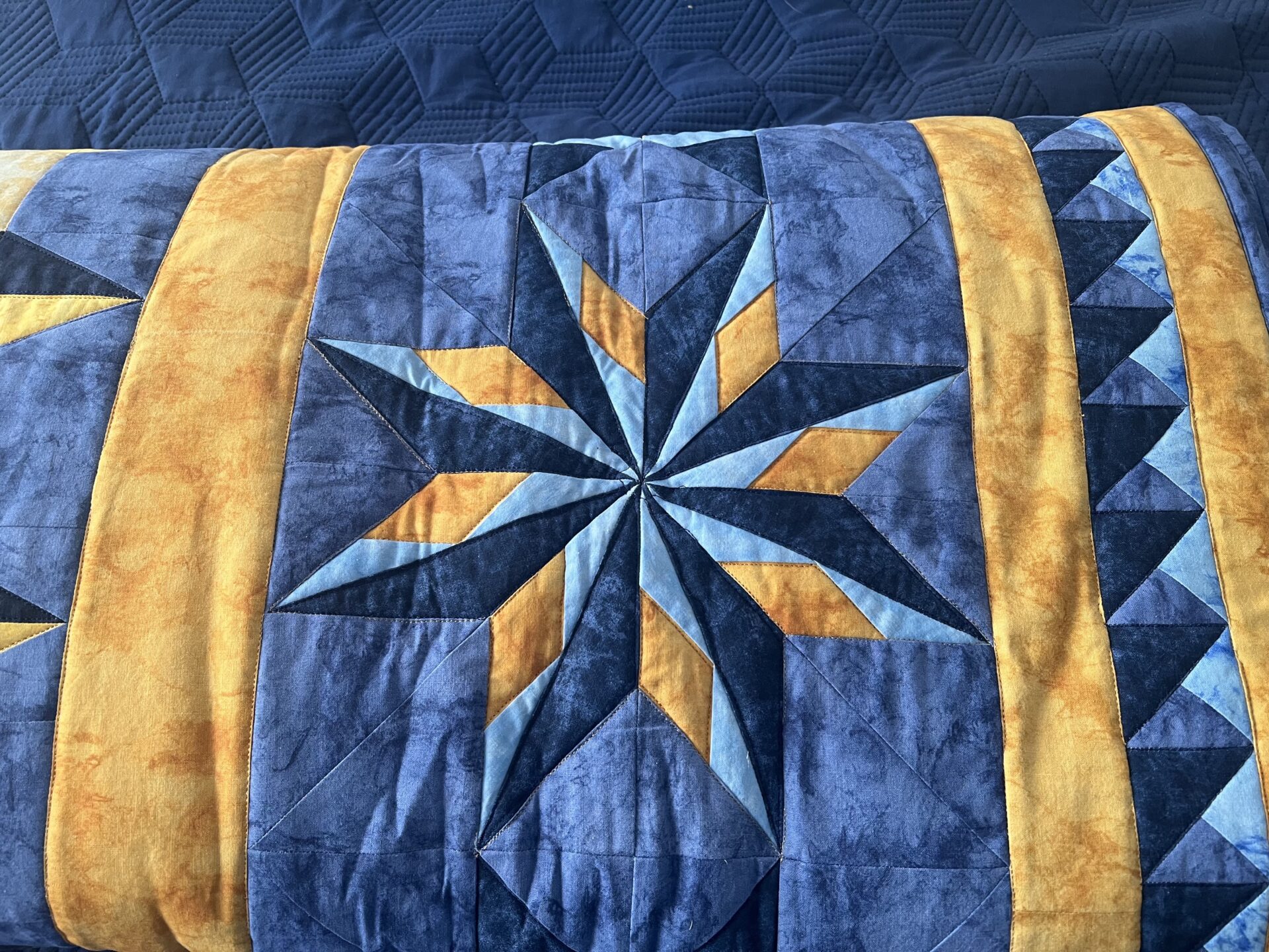 Folded up quilt with an eight sided star panel centered in the picture