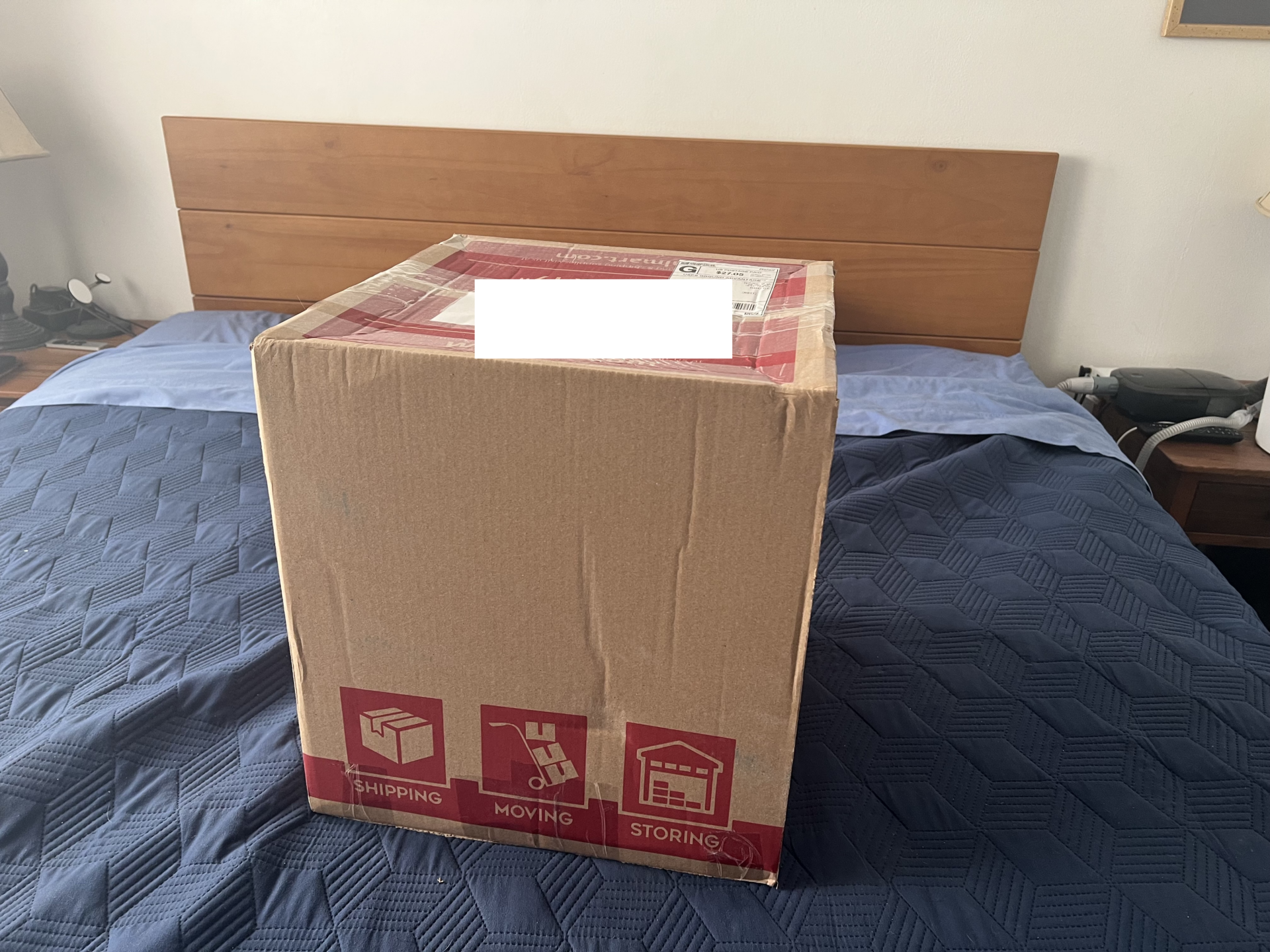 A cube shaped box sitting on a bed.