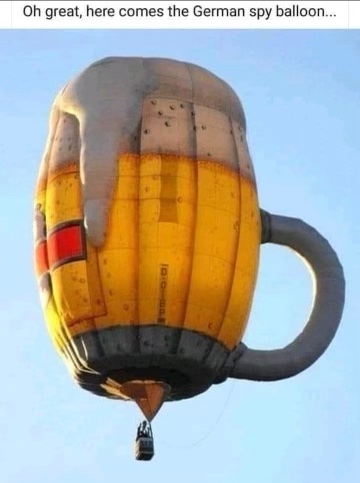 A hot air balloon shaped like a full mug of beer with the caption "Oh, great, here comes the German spy balloon!"