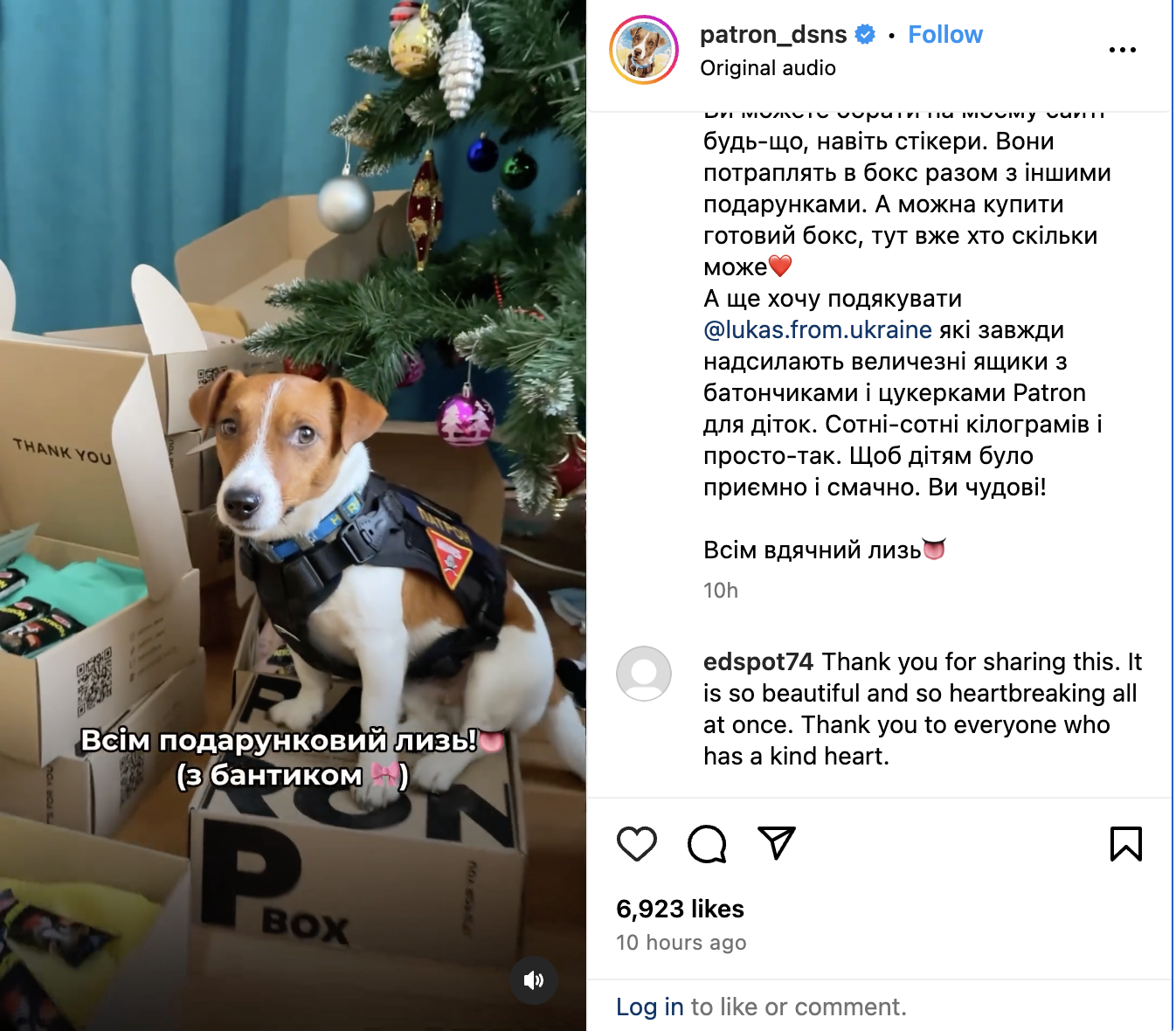 Screen shot of Patron the Ukrainian Sapper dog in his work harness sitting on a Patron box. Patron boxes are brown and have Patron written on them in Ukrainian Cyrillic. Patron is a brown and white short hair Jack Russell terrier. He is surrounded by other Patron boxes, some open. Each box is a charitable gift box for Ukrainian children who have either been wounded during the war and/or are orphans. They are available for purchase on Patron's shop site.