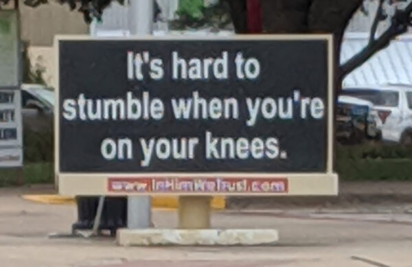 Sign saying "It's hard to stumble when you're on your knees"