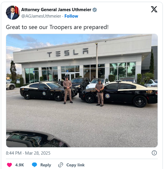 Two Florida Highway Patrol cars and troopers standing in front of a Tesla dealership.