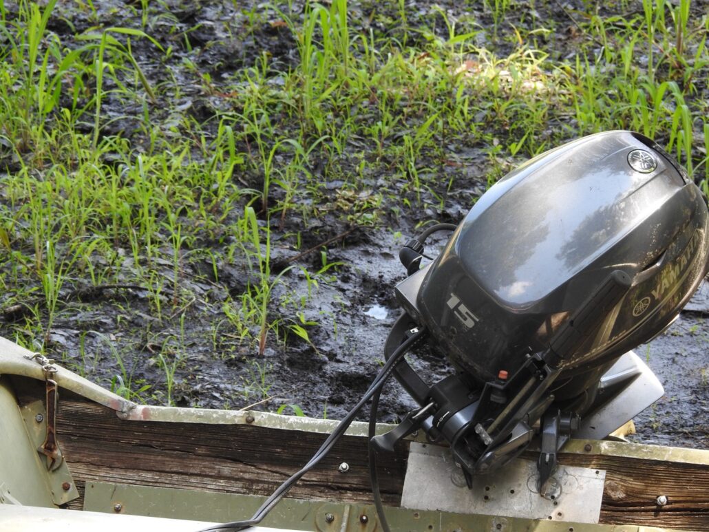 Outboard motor with tracks in the mud below.
