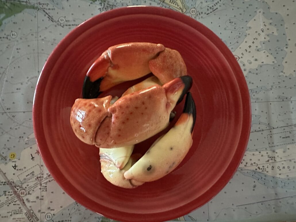 Three crab claws resting on a paprika colored plate.