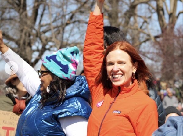 Grace in red at No Kings demonstration next to woman in blue