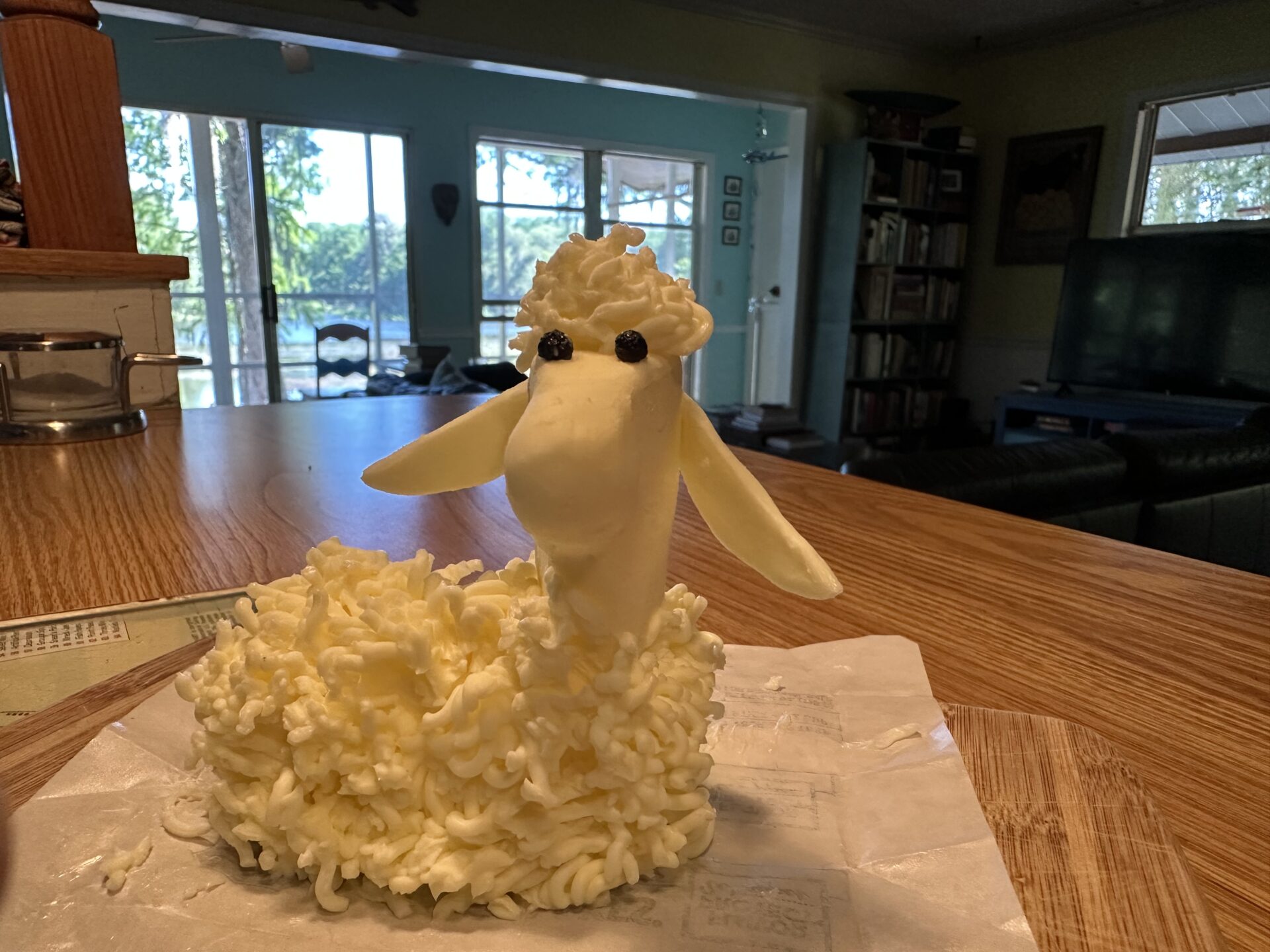 Lamb made out of butter with peppercorn eyes on a counter.