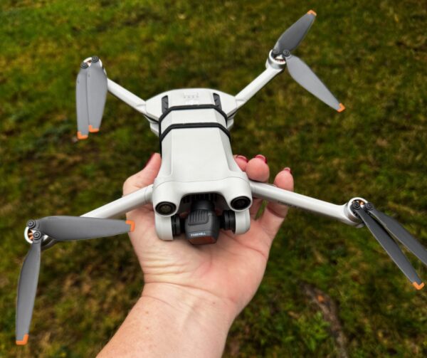 A DJI Mini drone, which is only slightly bigger than the hand holding it.